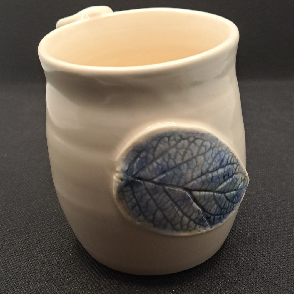 Handcrafted pottery mug with leaf.